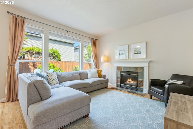 living area featuring a tiled fireplace, wood finished floors, and baseboards
