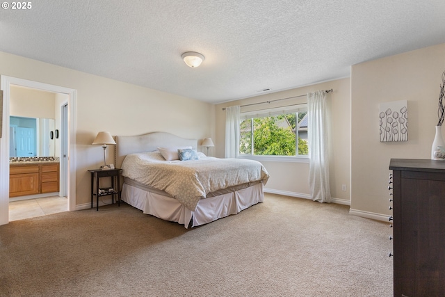 bedroom with light carpet, a textured ceiling, ensuite bath, and baseboards