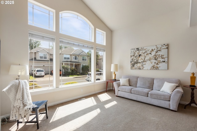 living area with carpet flooring, healthy amount of natural light, high vaulted ceiling, and baseboards