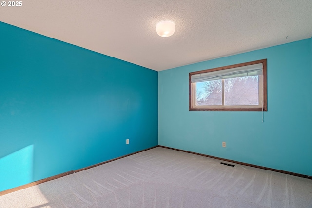 carpeted spare room with a textured ceiling