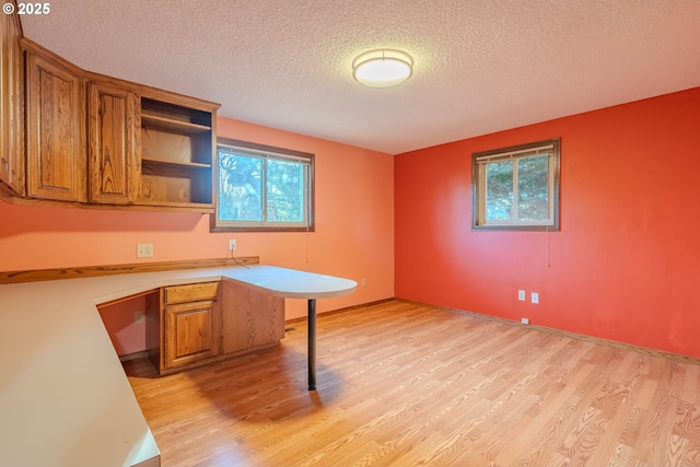 kitchen featuring light hardwood / wood-style floors, a kitchen bar, a textured ceiling, and kitchen peninsula