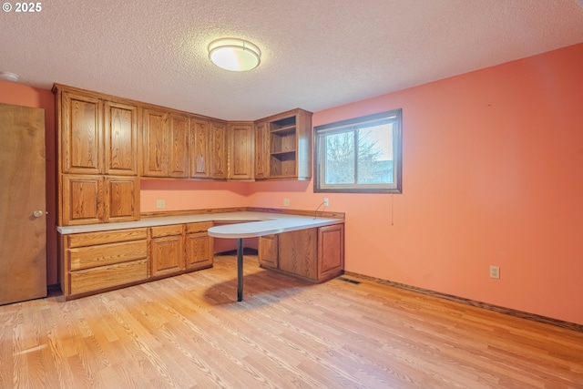 home office with a textured ceiling and light wood-type flooring