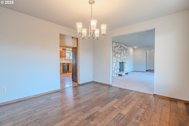 spare room with a notable chandelier, hardwood / wood-style floors, and a fireplace