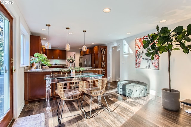 kitchen featuring hardwood / wood-style floors, decorative light fixtures, stainless steel fridge, and kitchen peninsula