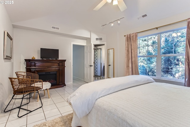 bedroom with ceiling fan, rail lighting, vaulted ceiling, and light tile patterned floors