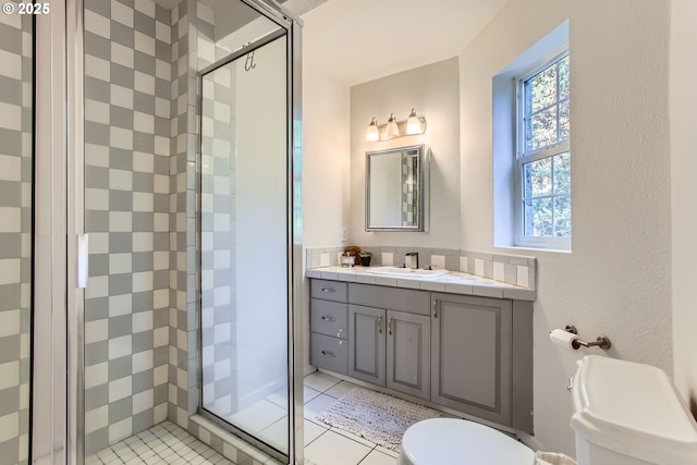 bathroom with tile patterned flooring, vanity, a shower with door, and toilet