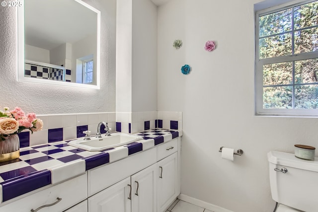 bathroom featuring decorative backsplash, a healthy amount of sunlight, toilet, and vanity