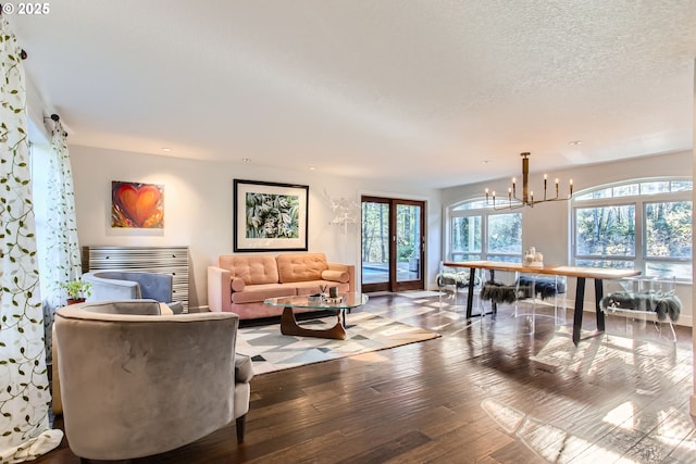 living room featuring a healthy amount of sunlight, a chandelier, hardwood / wood-style floors, and a textured ceiling