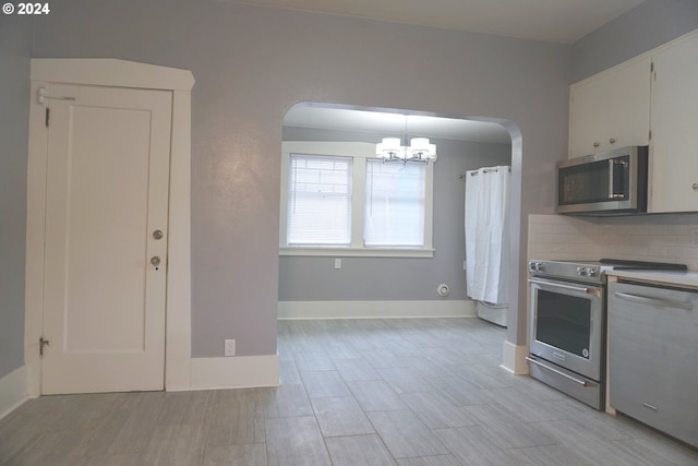 kitchen featuring white cabinetry, a notable chandelier, decorative light fixtures, decorative backsplash, and appliances with stainless steel finishes