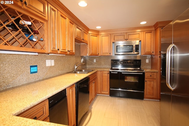 kitchen with black appliances, backsplash, light stone counters, and sink