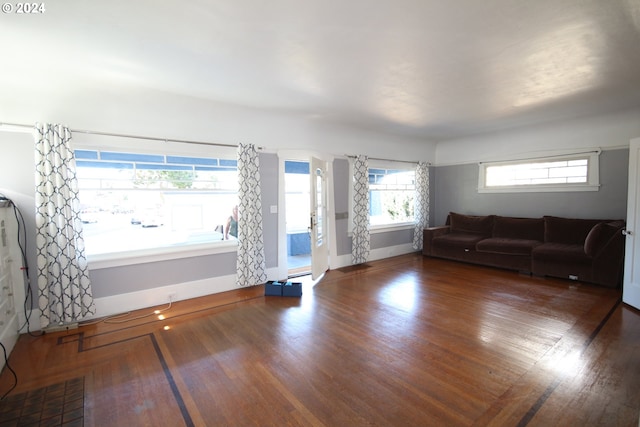 unfurnished living room featuring a healthy amount of sunlight and dark hardwood / wood-style floors