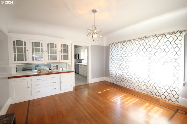 unfurnished dining area featuring a notable chandelier and hardwood / wood-style flooring