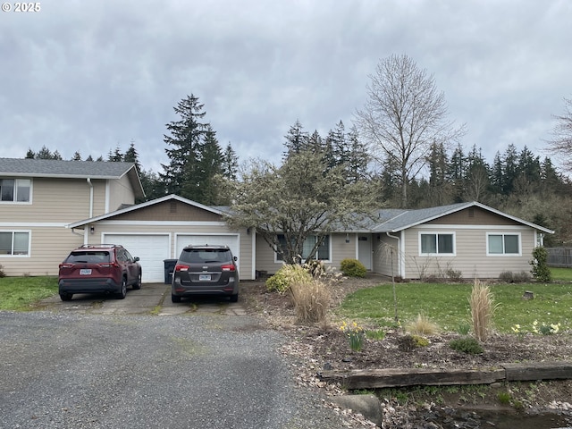 view of front facade featuring an attached garage, a front lawn, and gravel driveway