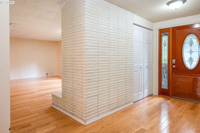 foyer with light hardwood / wood-style floors and a textured ceiling