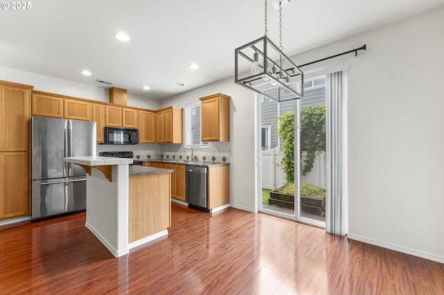 9234 SW Cascara Ln, Tualatin, OR 97062 - kitchen with appliances with stainless steel finishes, a chandelier, a center island, dark wood-type flooring, and recessed lighting