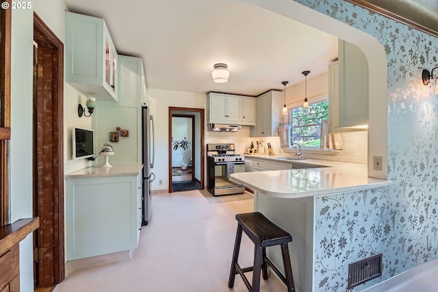 1834 SE 20th Ave, Portland, OR 97214 - kitchen with gas range oven, under cabinet range hood, a kitchen breakfast bar, a peninsula, and decorative backsplash