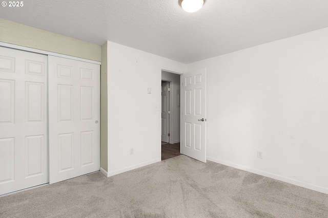 unfurnished bedroom with a textured ceiling, a closet, and light carpet