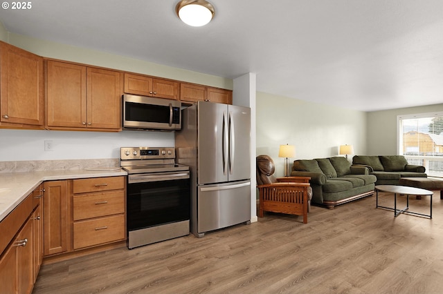 kitchen with appliances with stainless steel finishes and light hardwood / wood-style floors