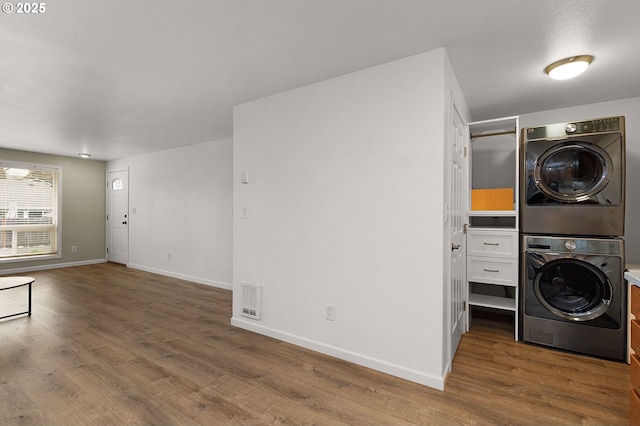 laundry room featuring stacked washer and clothes dryer and dark wood-type flooring