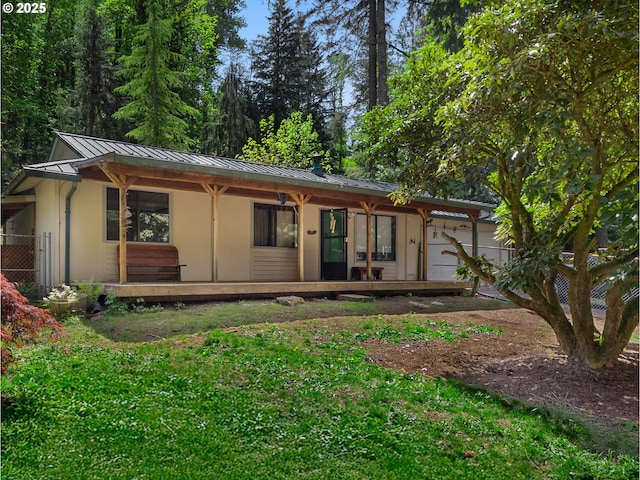 rear view of property with stucco siding, metal roof, a porch, a yard, and a standing seam roof