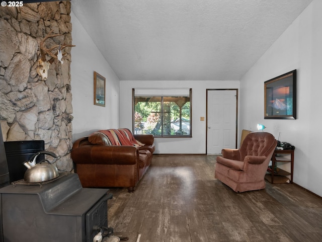 living room with a wood stove, lofted ceiling, a textured ceiling, and wood finished floors