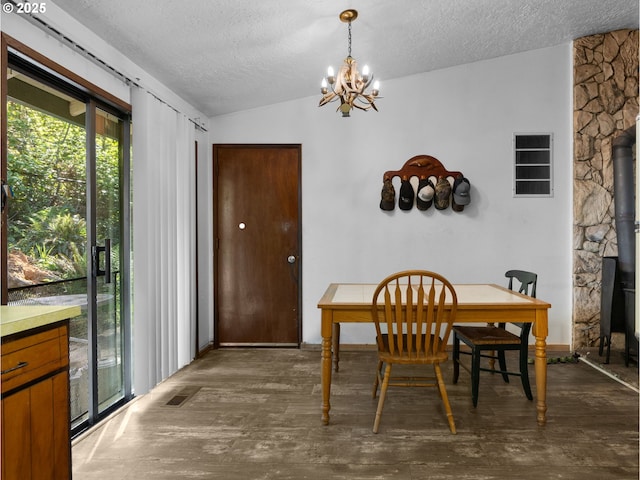 dining space with an inviting chandelier, a textured ceiling, dark wood-type flooring, and lofted ceiling