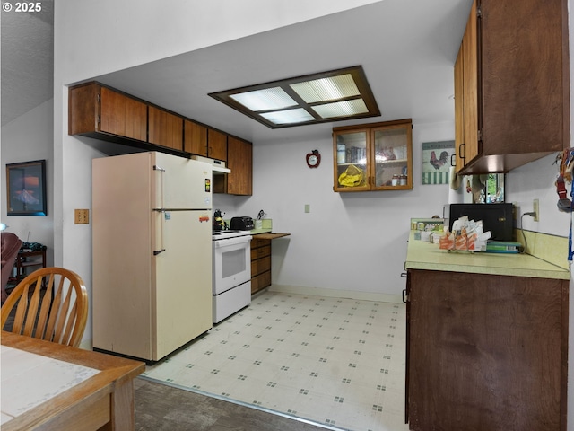 kitchen featuring white appliances, exhaust hood, light floors, light countertops, and baseboards