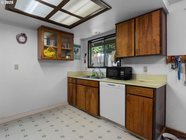kitchen with a sink, light floors, black microwave, light countertops, and white dishwasher