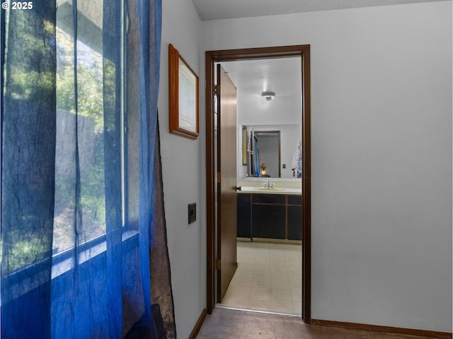 corridor featuring baseboards and a sink
