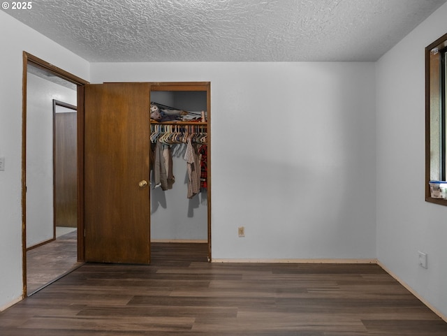unfurnished bedroom with a walk in closet, a textured ceiling, a closet, and wood finished floors