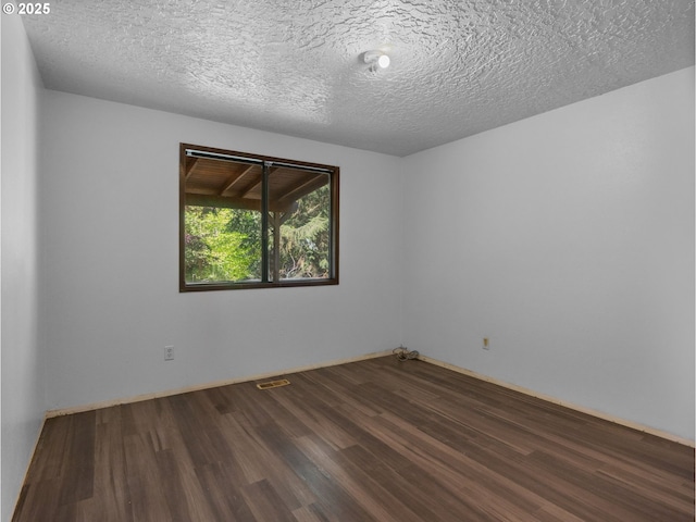 empty room featuring a textured ceiling, visible vents, and wood finished floors