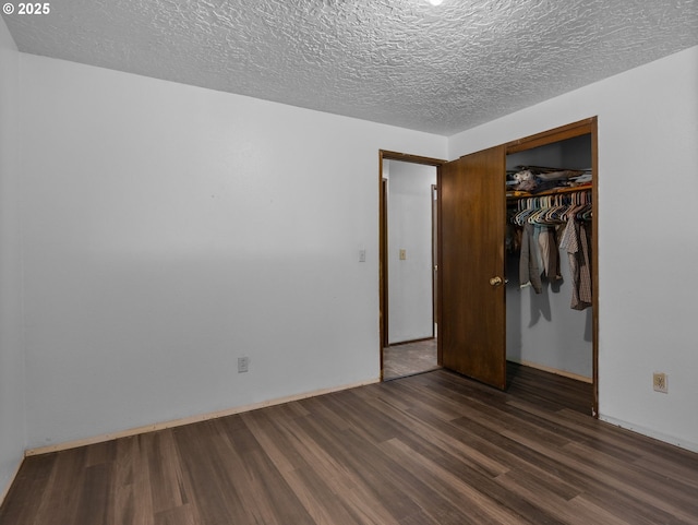unfurnished bedroom with a textured ceiling, a closet, dark wood-style floors, and baseboards