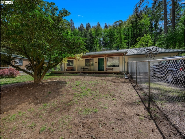 ranch-style house with a standing seam roof, fence, metal roof, a garage, and a porch