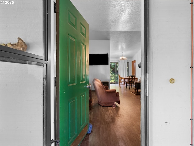 foyer entrance with an inviting chandelier, a textured ceiling, and wood finished floors