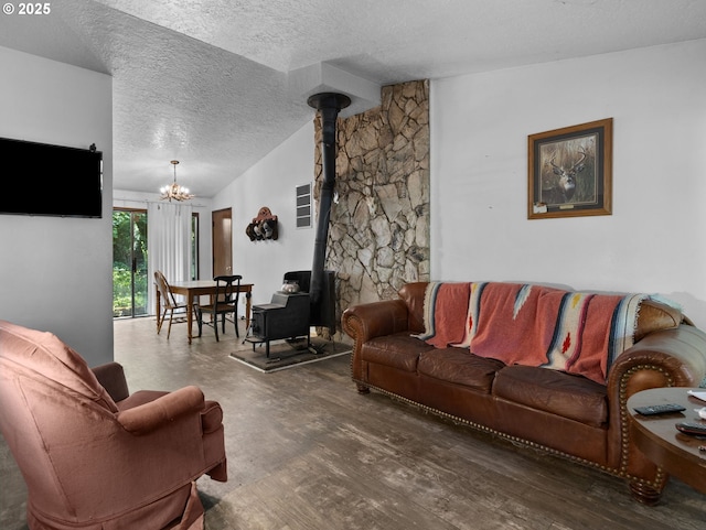 living room featuring vaulted ceiling, wood finished floors, a textured ceiling, a wood stove, and a chandelier