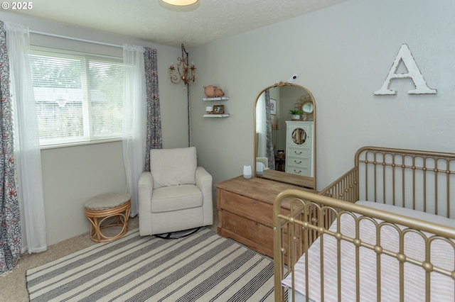 carpeted bedroom with a crib and a textured ceiling