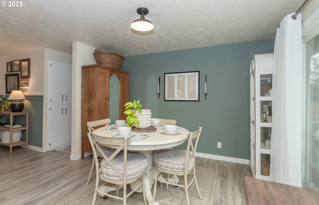 dining area with light hardwood / wood-style floors and a textured ceiling