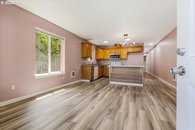 2251 SE 139th Ave, Portland, OR 97233 - kitchen with stainless steel microwave, white dishwasher, a chandelier, brown cabinets, and light wood-type flooring