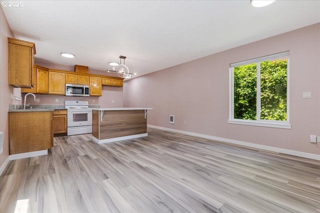 2251 SE 139th Ave, Portland, OR 97233 - kitchen featuring white range with electric cooktop, stainless steel microwave, light countertops, a chandelier, and brown cabinetry