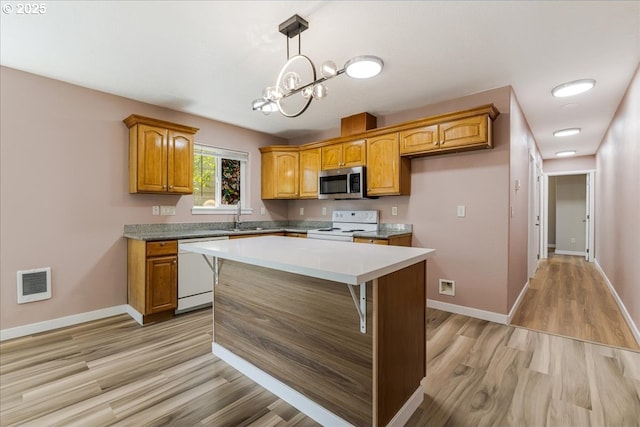 2251 SE 139th Ave, Portland, OR 97233 - kitchen featuring white appliances, light wood-style floors, brown cabinets, a chandelier, and decorative light fixtures