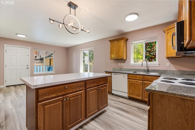 2251 SE 139th Ave, Portland, OR 97233 - kitchen featuring dishwasher, light wood finished floors, a kitchen island, brown cabinets, and stainless steel microwave