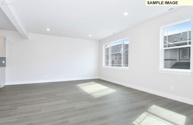 empty room with beam ceiling and dark wood-type flooring