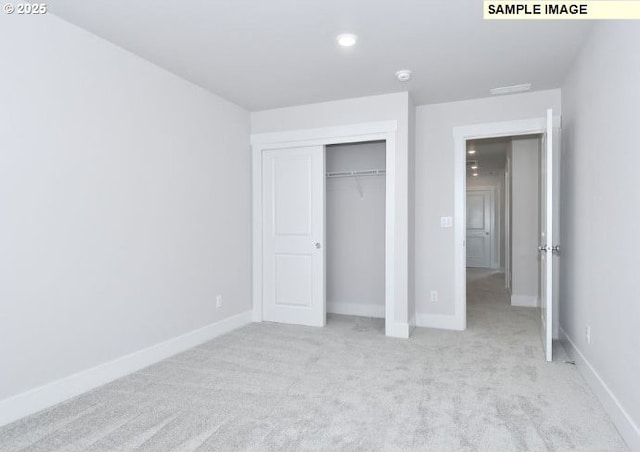 unfurnished bedroom with light carpet and a closet