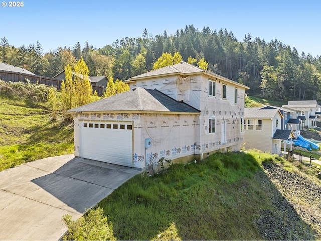 view of front facade featuring driveway, roof with shingles, and a garage