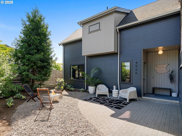 back of house with a patio area, fence, and roof with shingles