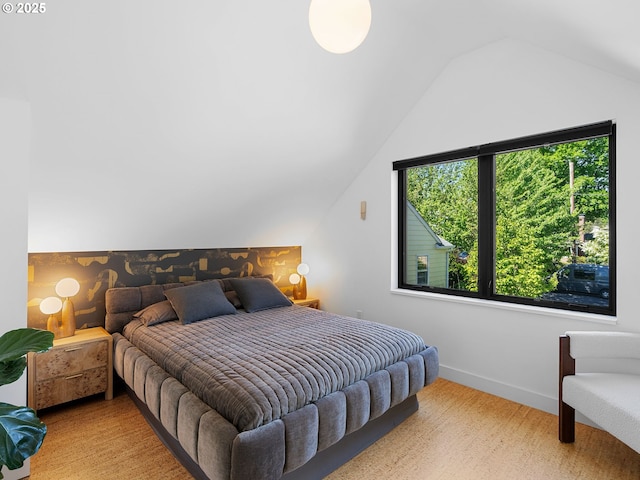 bedroom featuring lofted ceiling, baseboards, and wood finished floors