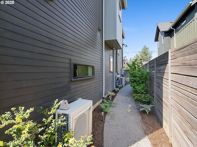 view of side of home with fence, ac unit, and central air condition unit
