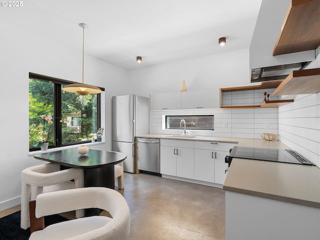 kitchen featuring appliances with stainless steel finishes, a sink, tasteful backsplash, white cabinets, and finished concrete floors