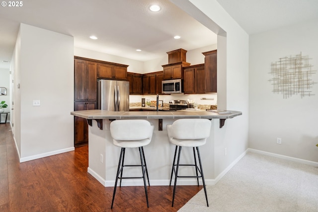 16125 SE Kingbird Dr, Clackamas, OR 97015 - kitchen with stainless steel appliances, a peninsula, a kitchen bar, recessed lighting, and baseboards