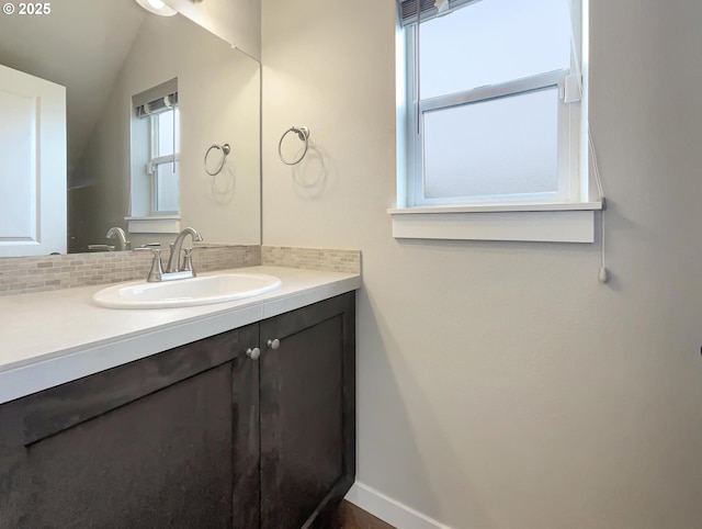 bathroom with tasteful backsplash, lofted ceiling, vanity, and baseboards